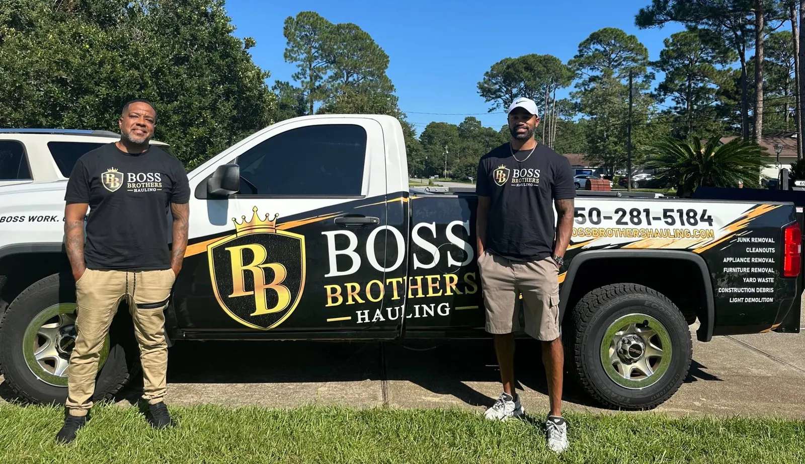 The two Boss Brothers standing either side of their wrapped hauling truck