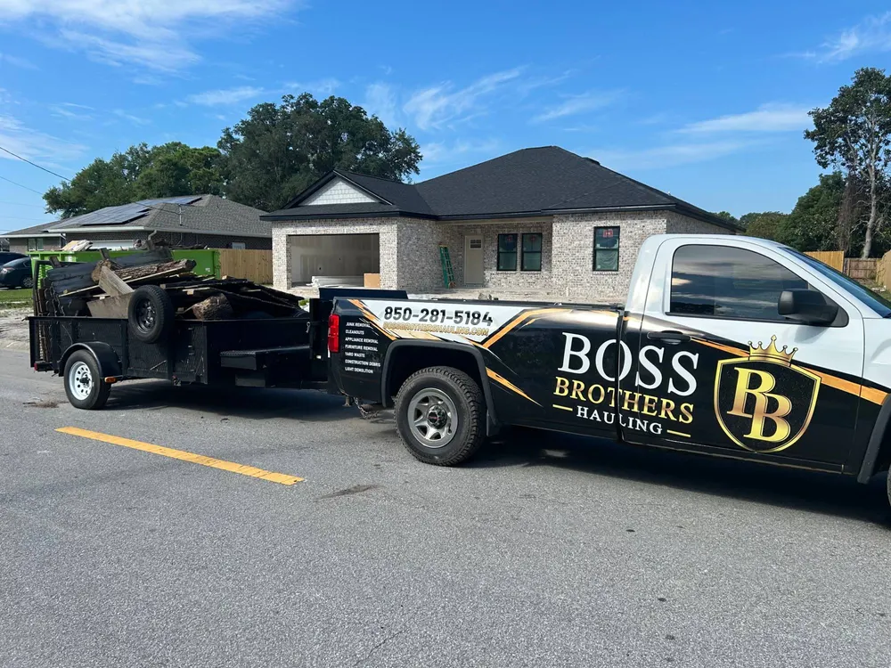The Boss Brothers truck and trailer loaded with lumber outside the same house